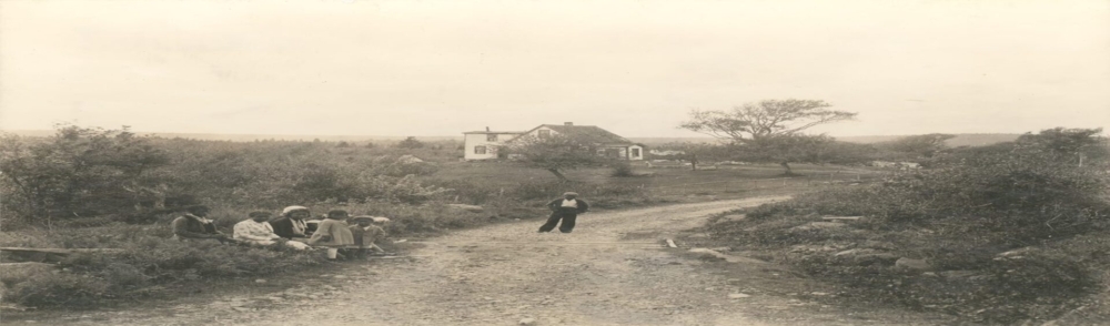 A group of children on a dirt road, with a building in the background. - 