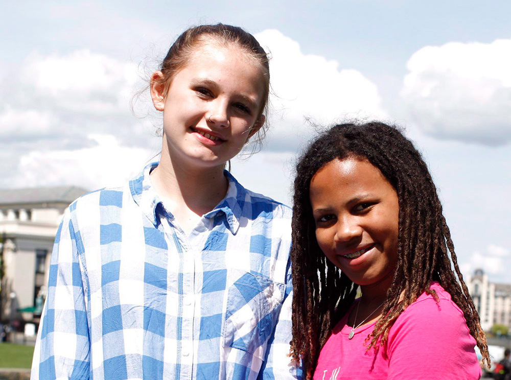 Deux jeunes filles debout sur une pelouse devant un bâtiment gouvernemental. Two girls standing on a lawn in front of a government building.