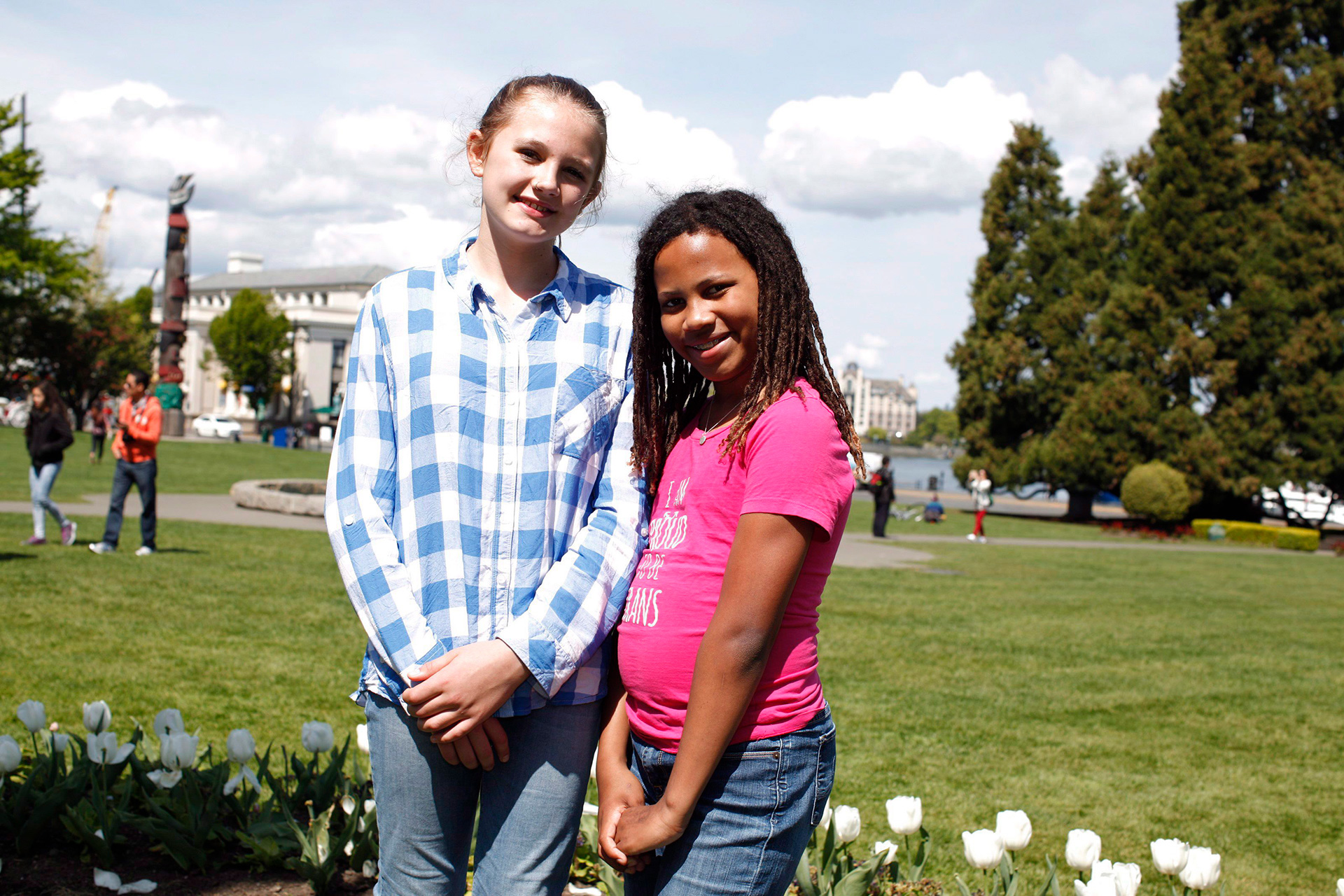 Two girls standing on a lawn in front of a government building.