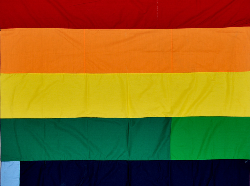 Partie d’une bannière cousue avec des bandes de tissu horizontales colorées. Portion of a banner sewn with coloured horizontal stripes of fabric.