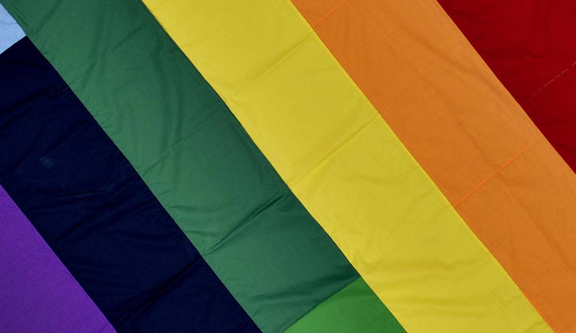A square section of a rainbow banner on a grey background.