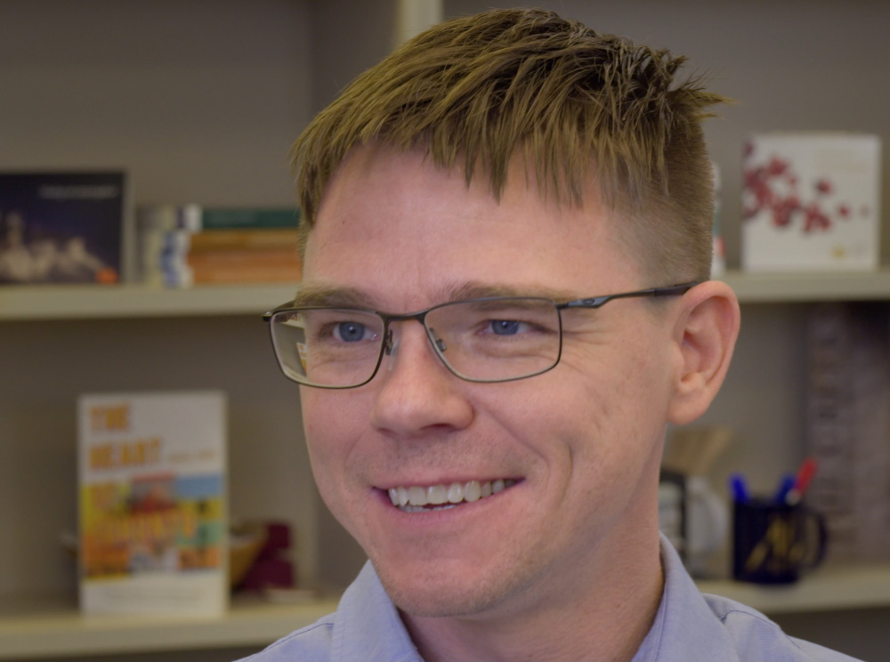 Screenshot of a video clip featuring Dr. Tom Hooper, a man with glasses in a light-coloured shirt.