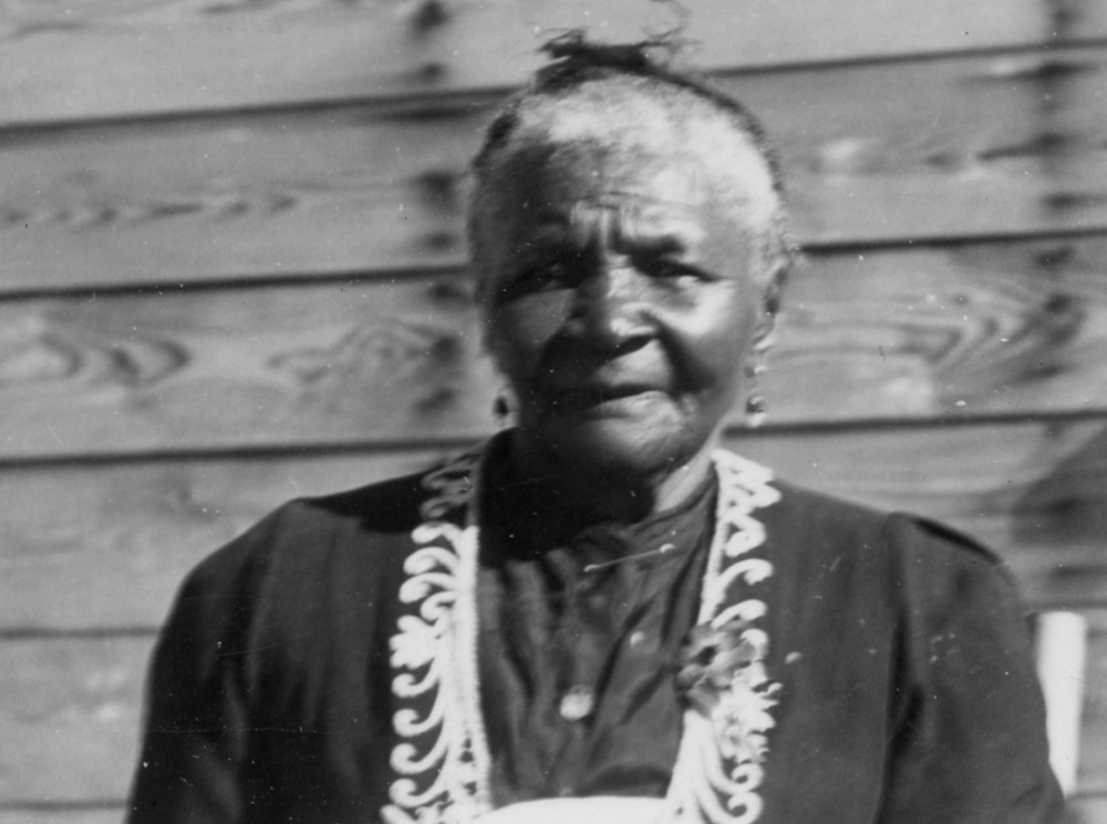 Black-and-white photograph of Mattie Mayes standing outside a building.