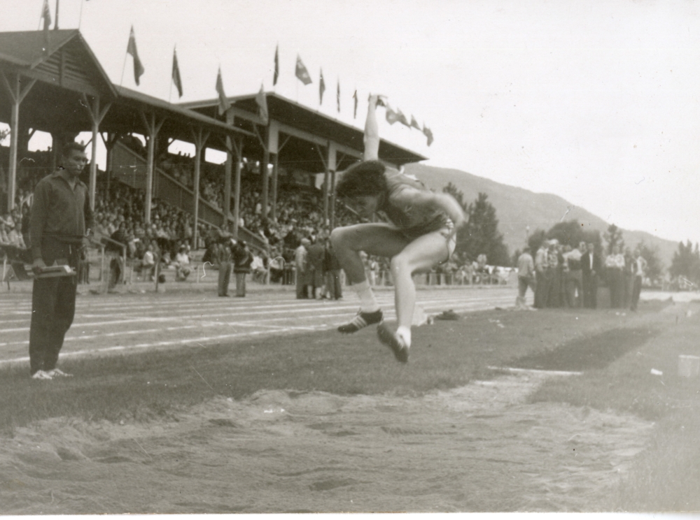 Photographie en noir et blanc de Valerie Jerome effectuant le saut en longueur sous le regard de son frère.