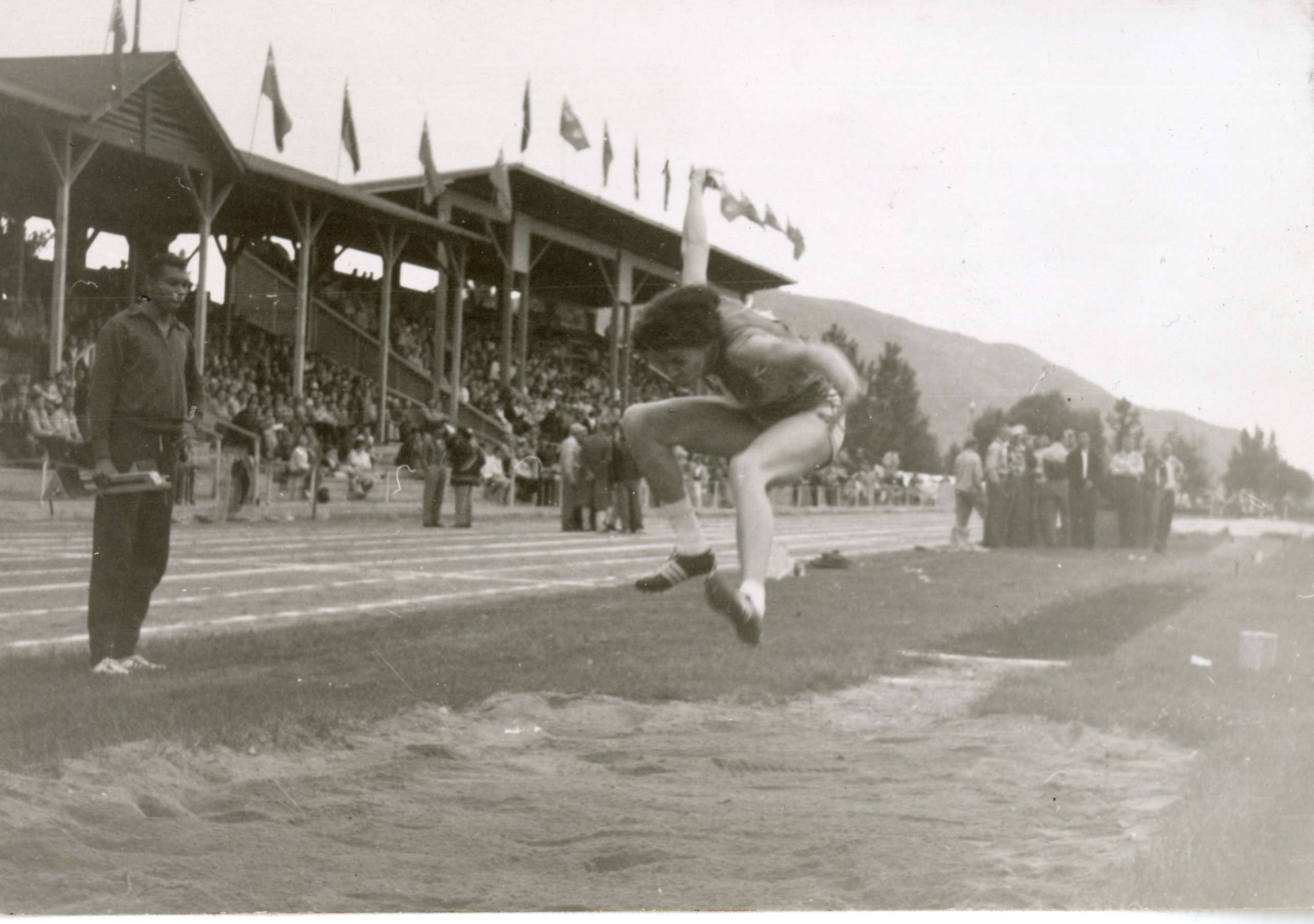 Photographie en noir et blanc de Valerie Jerome effectuant le saut en longueur sous le regard de son frère.