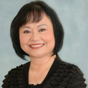 Une photo d’une Vietnamienne souriante aux cheveux noirs courts qui porte une chemise noire.